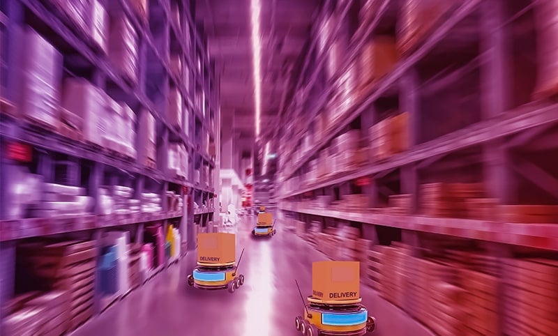Eine Hand im Vordergrund hält ein Smartphone, auf dem eine App zur intelligenten Überwachung angezeigt wird. Im Hintergrund sind Industriemotoren zu sehen.